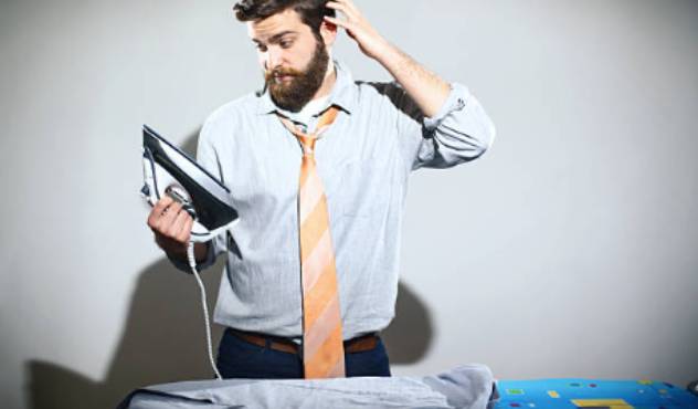A man holding an iron in front of an ironing board
